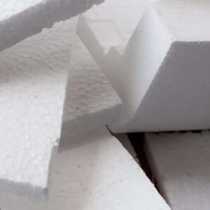 Prim-plan spumă albă de polistiren pe carton. Spuma de polistiren este material de amortizare în ambalaje, material pentru aplicații artizanale și altele.