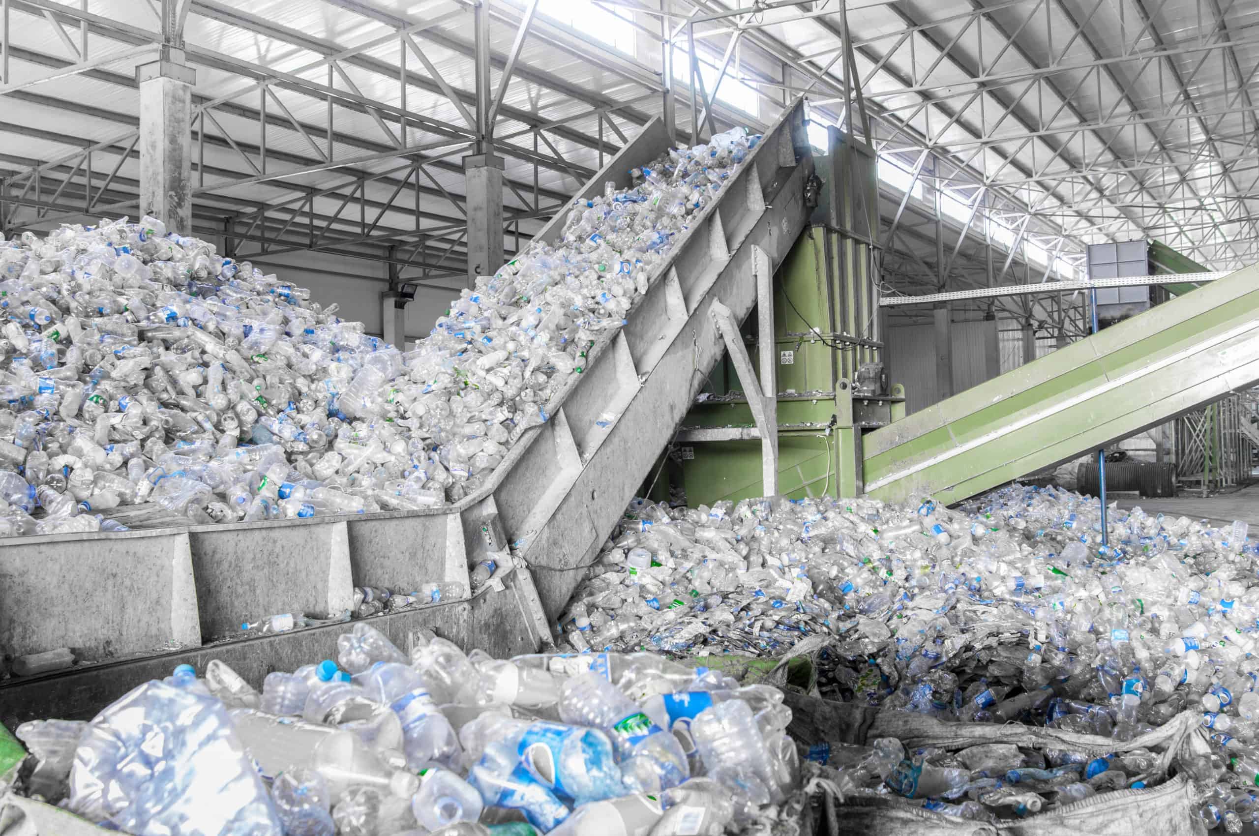 Nahaufnahme einer Rolltreppe mit einem Stapel von Kunststoffflaschen in der Fabrik für die Verarbeitung und das Recycling. PET-Recyclinganlage