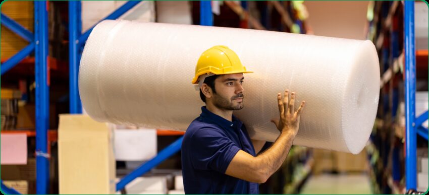 A man holding a bundle of used bubble wrap, demonstrating the act of recycling and responsible disposal of packaging materials