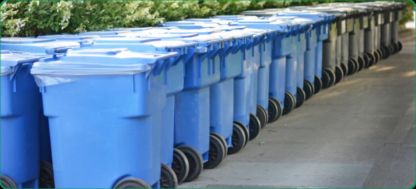 Mėlynų plastikinių šiukšliadėžių eilės, kuriose patogiai ir organizuotai galima išmesti perdirbti tinkamas medžiagas.